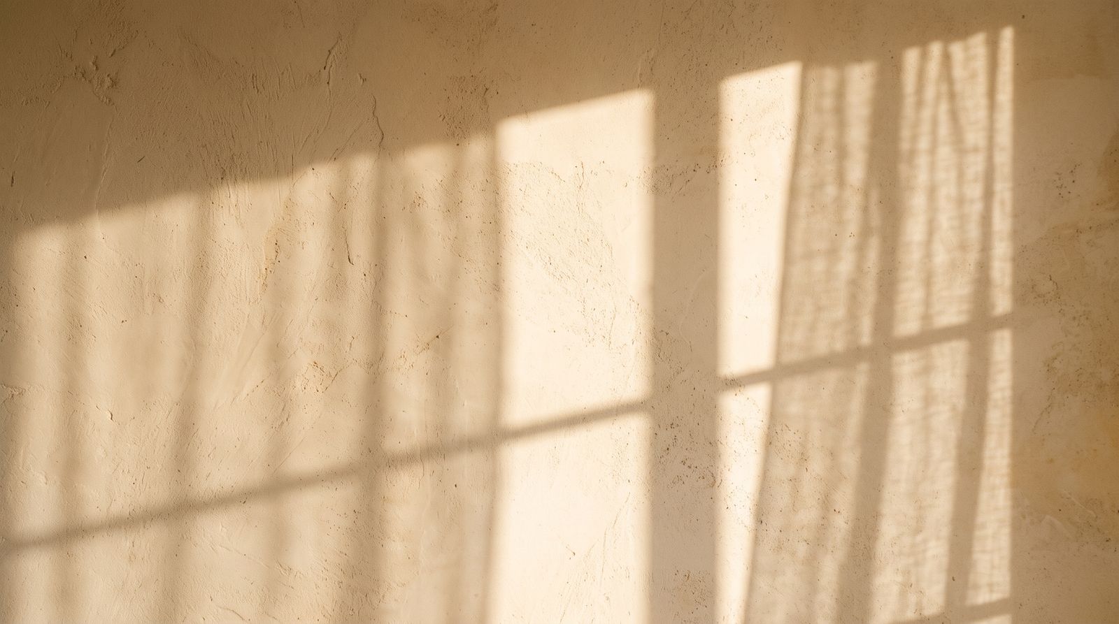 Luz de tarde proyectando sombras largas sobre una pared cálida